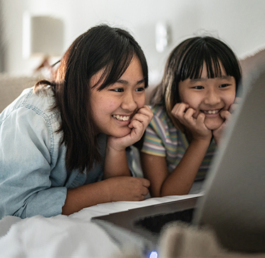 Two teens looking at a laptop screen smiling 